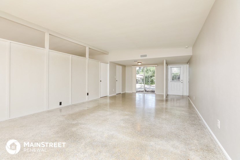 a large empty living room with white walls and concrete floors