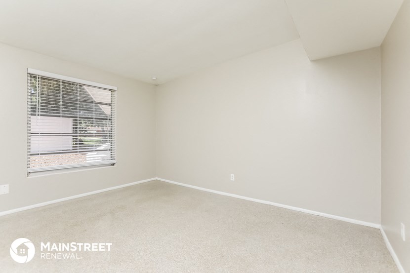 a bedroom with a window and a carpeted floor