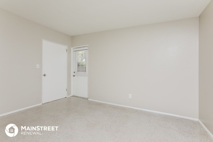the spacious living room of a home with white walls and carpet