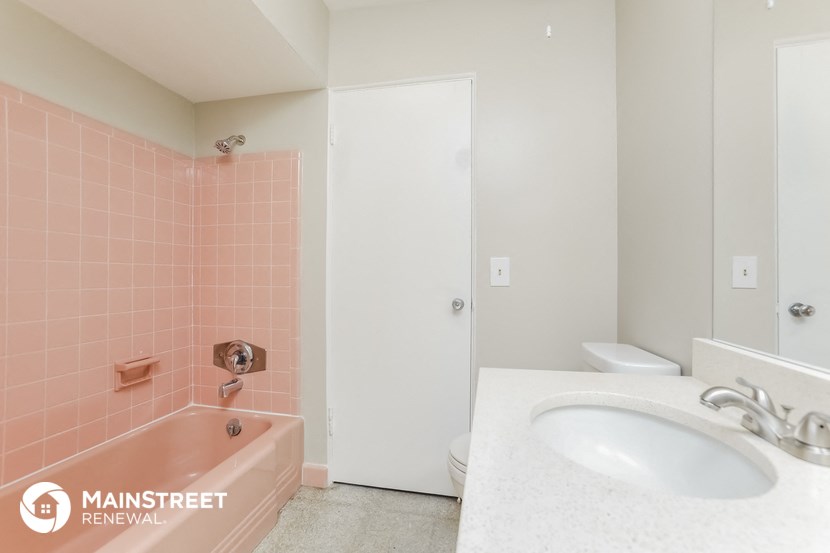 a pink bathroom with a sink and tub and a toilet