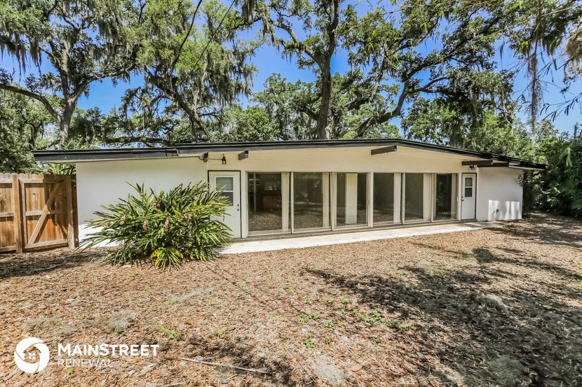 a small white house with a yard and trees