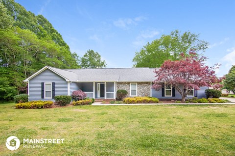 a blue house with a lawn and a red tree