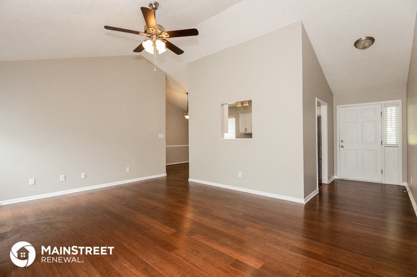 the living room and dining room with wood flooring and a ceiling fan