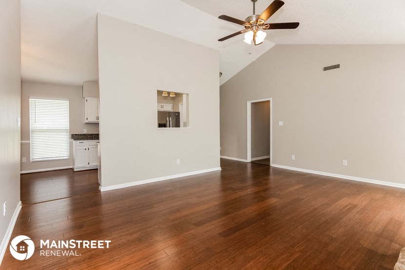 the living room and kitchen with hardwood flooring and a ceiling fan
