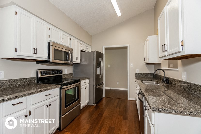 a kitchen with white cabinets and granite counter tops and stainless steel appliances
