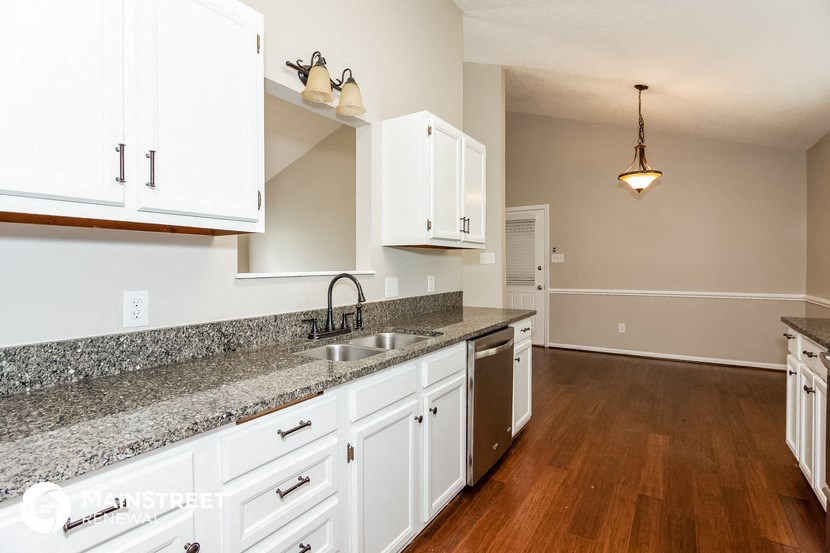 a kitchen with white cabinets and granite counter tops and a sink