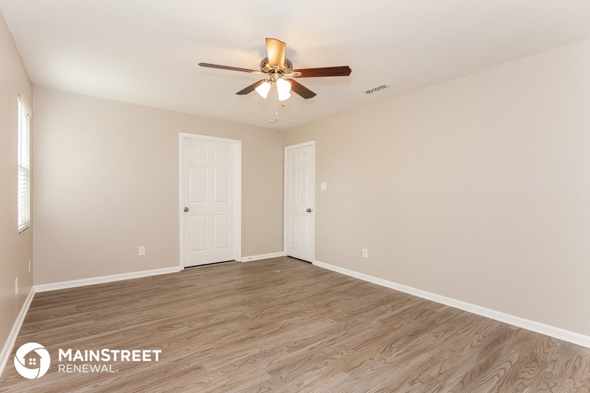 the spacious living room with wood flooring and a ceiling fan
