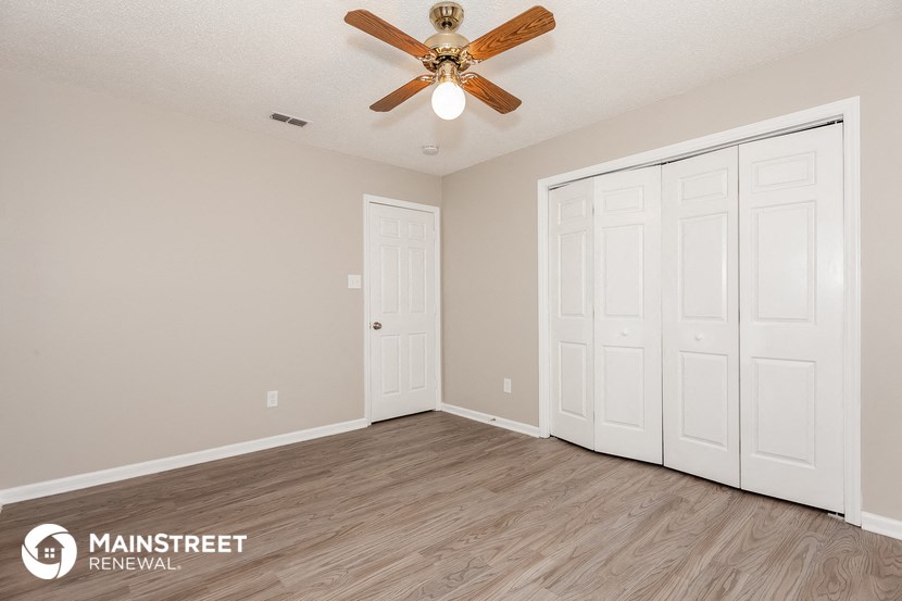 the spacious living room of this manufactured home has a ceiling fan and two closets