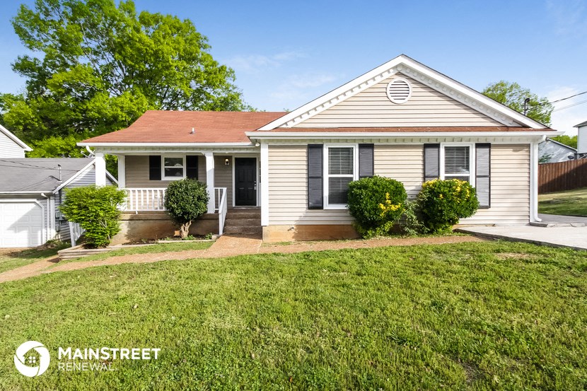 a small white house with a lawn and a porch