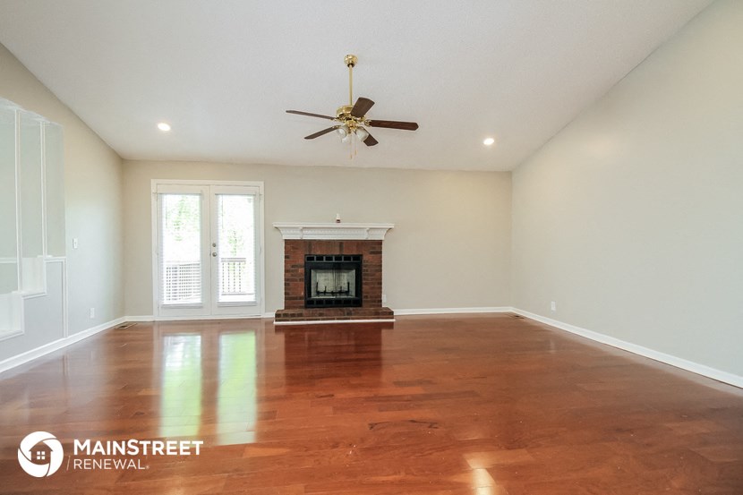 an empty living room with a fireplace and a ceiling fan