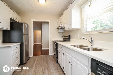 a kitchen with white cabinets and a sink and a refrigerator