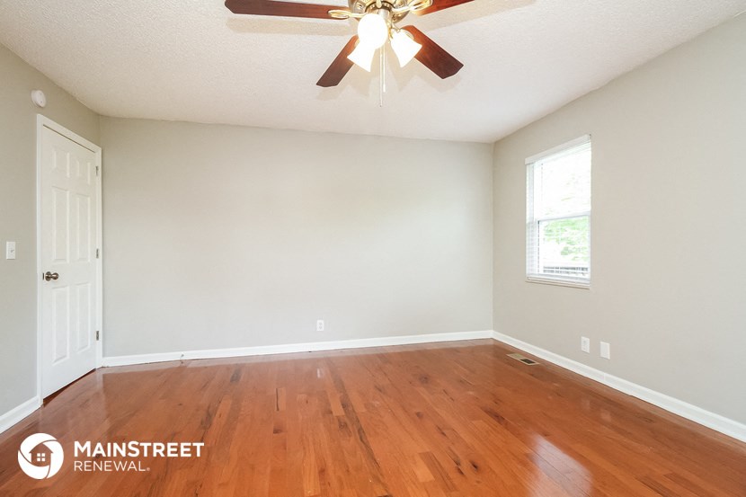 the bedroom of this home has a hardwood floor and a ceiling fan