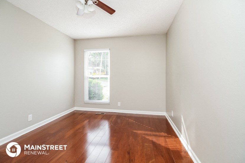 the spacious living room with hardwood flooring and a window