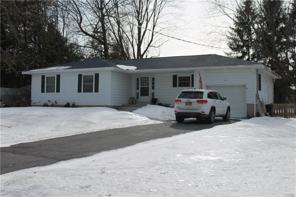 A white car is parked in front of a house.