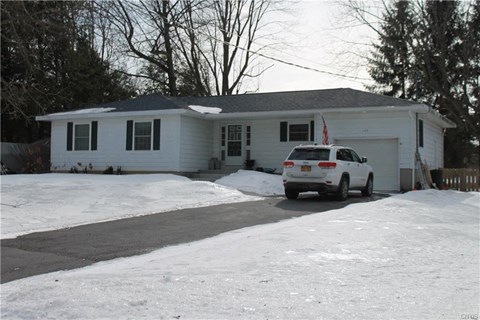 A white car is parked in front of a house.