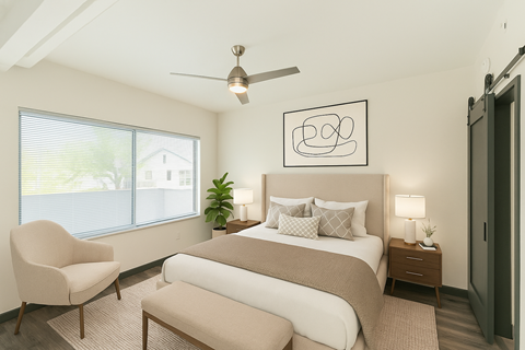 A bedroom with a large bed, a chair, and a ceiling fan.