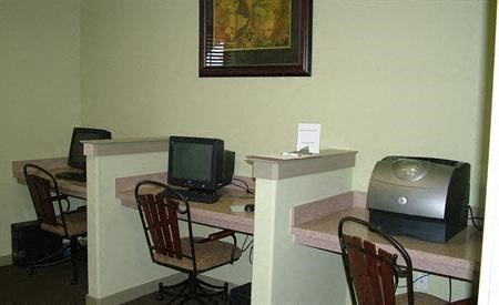 a room with a desk with a computer and a television