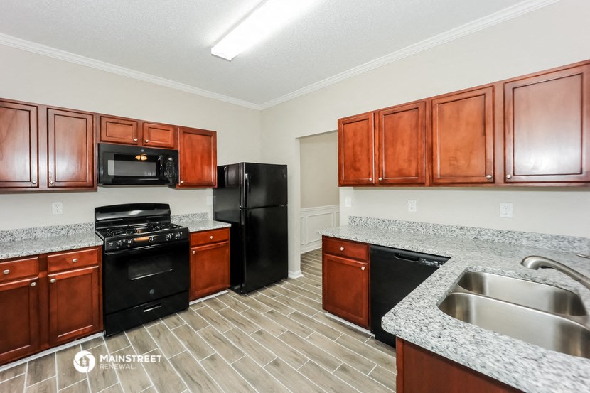 a kitchen with wood cabinets and black appliances and granite counter tops
