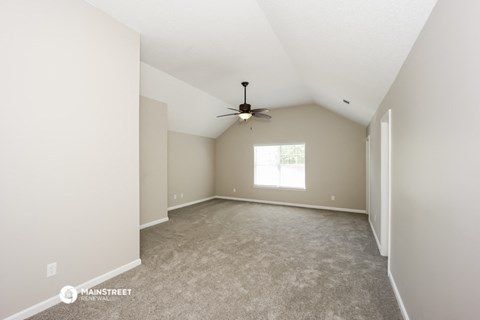 the spacious living room with ceiling fan and carpet