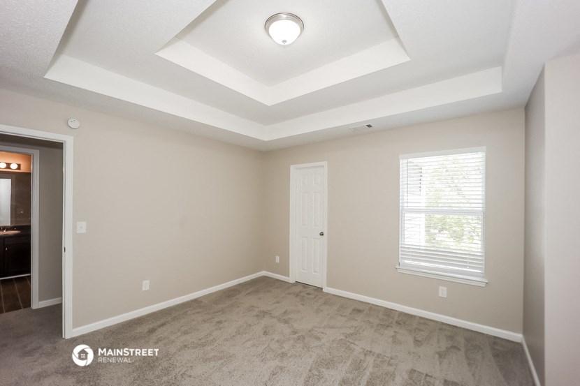 the spacious living room with a coffered ceiling and a door to the kitchen