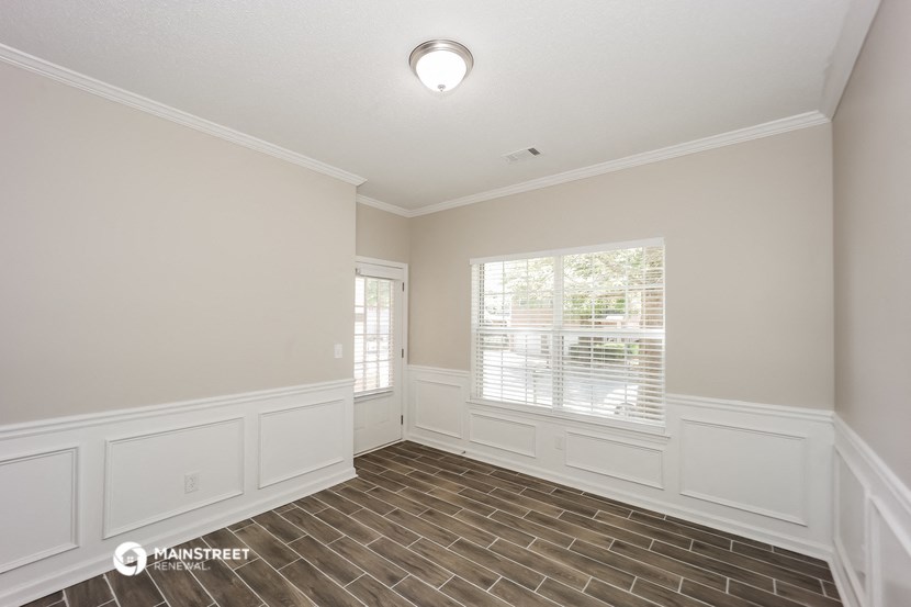 the spacious living room with wood flooring and white walls