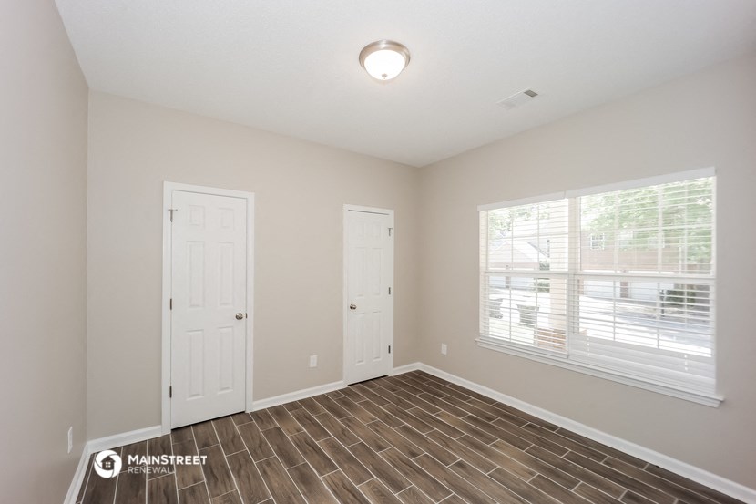 the spacious living room with two doors and a window