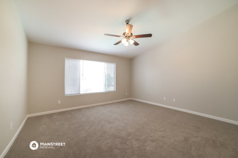 an empty living room with a ceiling fan and a window