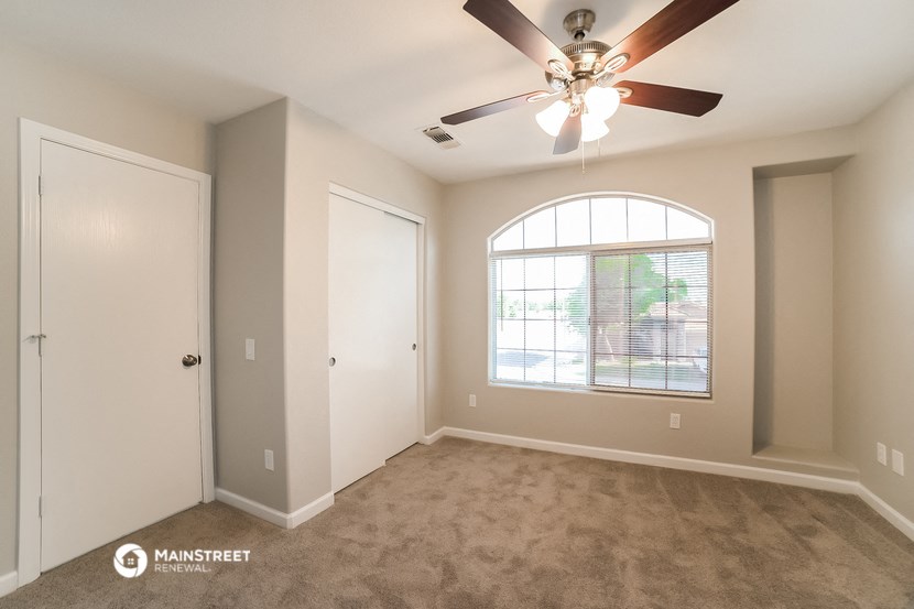 an empty living room with a ceiling fan and a window