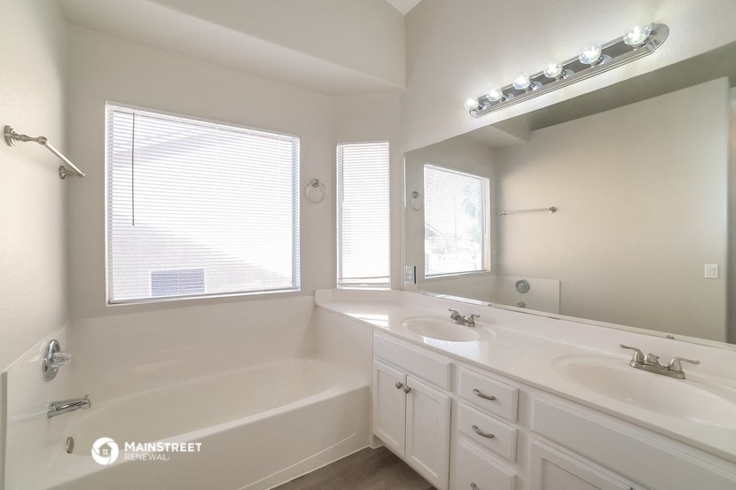 a bathroom with two sinks and a tub and a large mirror