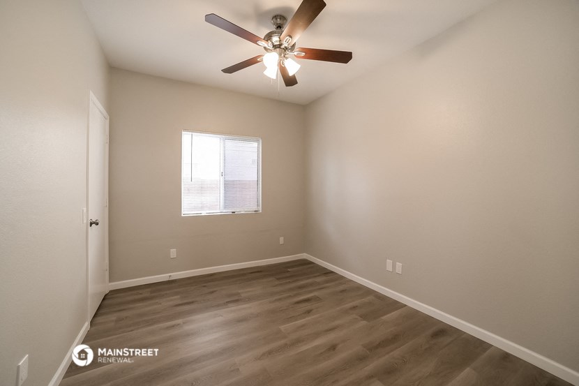 the spacious living room with ceiling fan and wood flooring