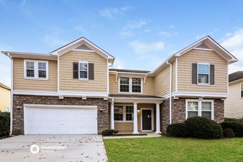 a beige and brick house with a white garage door