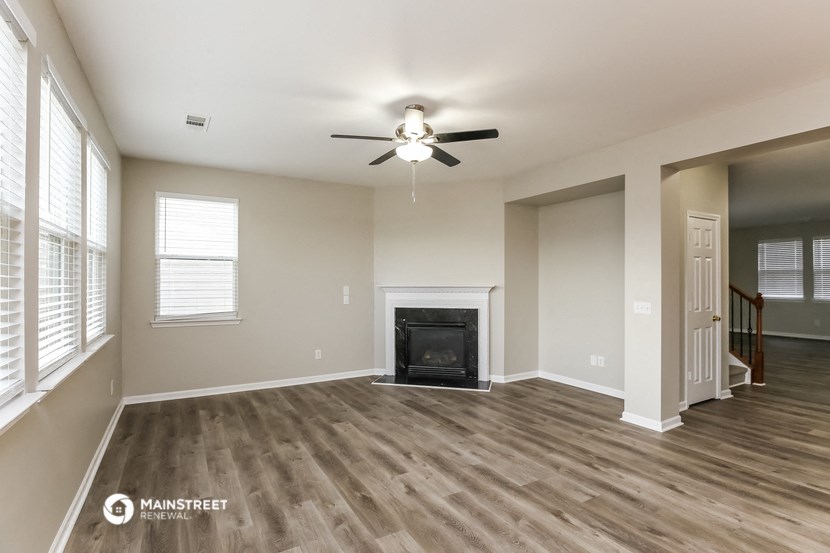 a living room with a fireplace and a ceiling fan