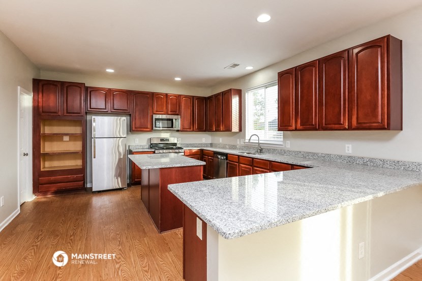 an updated kitchen with granite counter tops and wooden cabinets