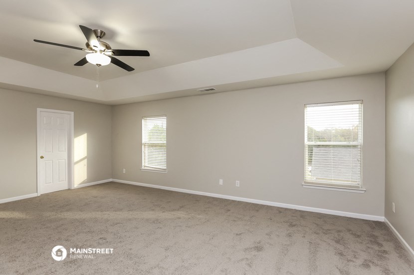 an empty room with a ceiling fan and two windows