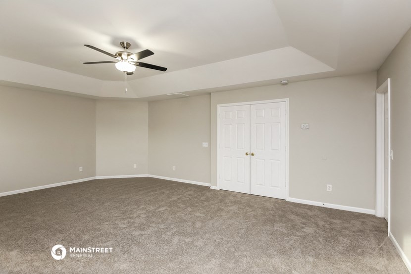an empty living room with a ceiling fan
