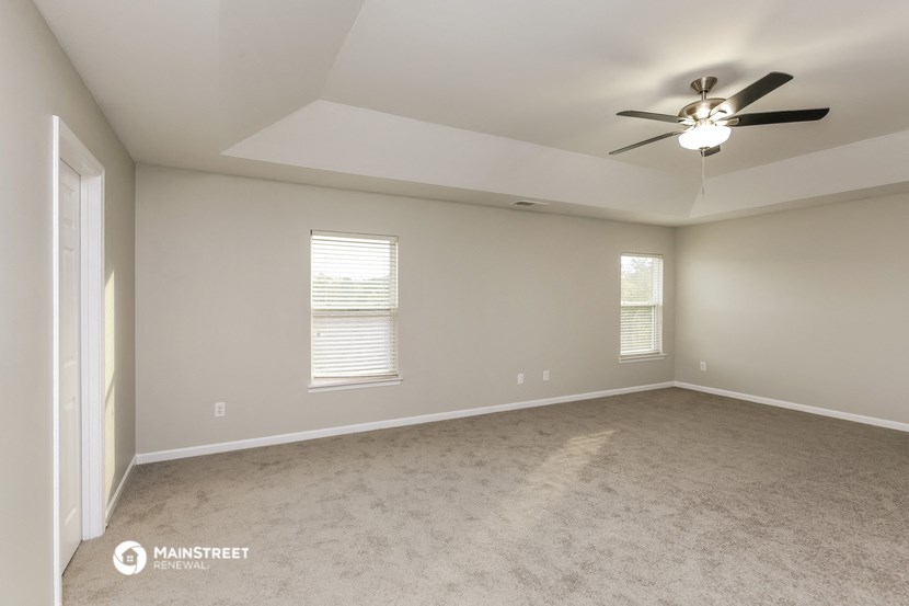 the spacious living room with ceiling fan and carpeting