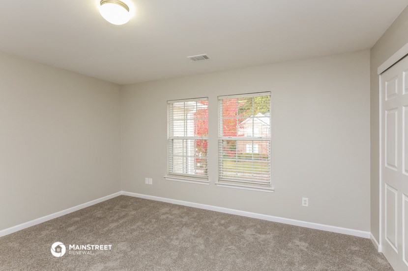 the spacious living room with two windows and carpeting