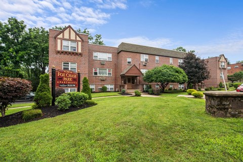 a large brick apartment building with a yard and a sign