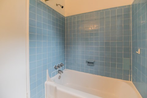a bathroom with blue tile and a white tub