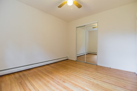 an empty room with wood flooring and a ceiling fan