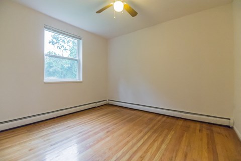 an empty living room with wood floors and a window