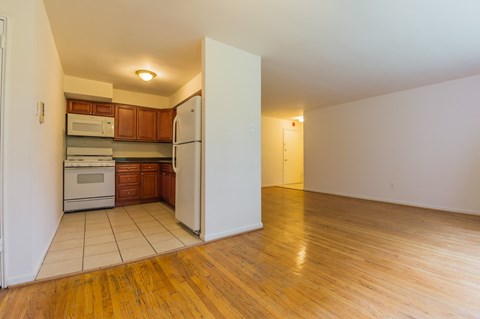an empty kitchen with a white refrigerator and a wood floor