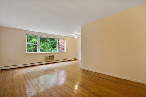 an empty living room with wood floors and a window