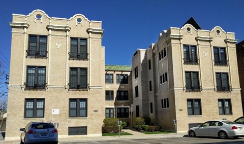 A tan building with a green roof and a car parked in front.