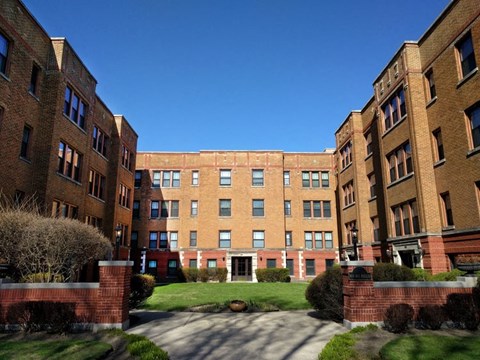 a large brick building with a green yard in front of it