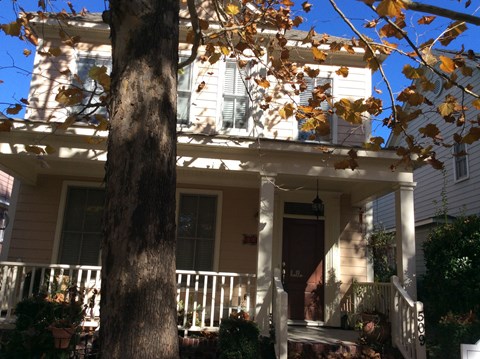 a house with a porch and a tree in front of it