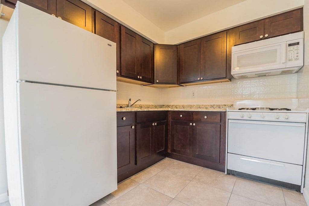 a kitchen with white appliances and dark wood cabinets