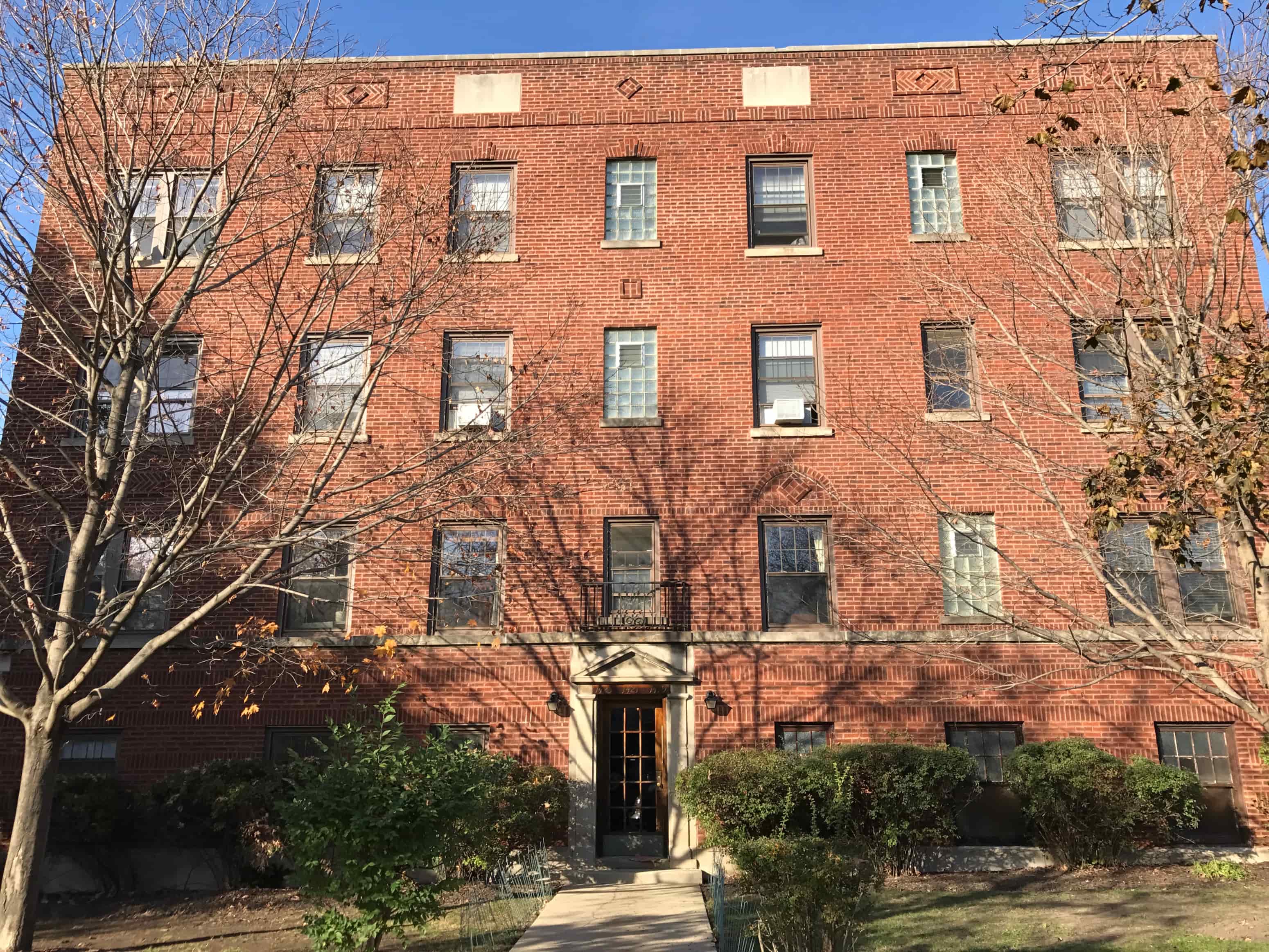 A red brick building with a tree in front.