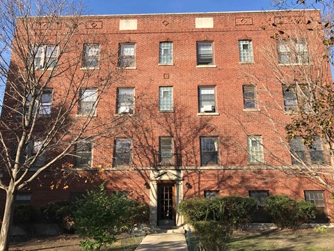 A red brick building with a tree in front.