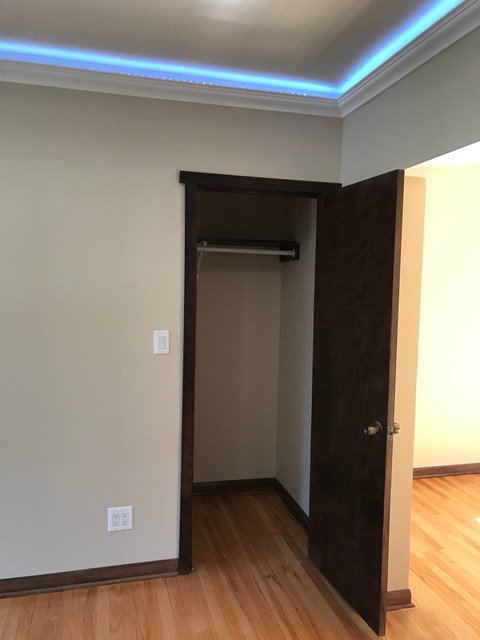A room with a brown door and a light switch on the wall.
